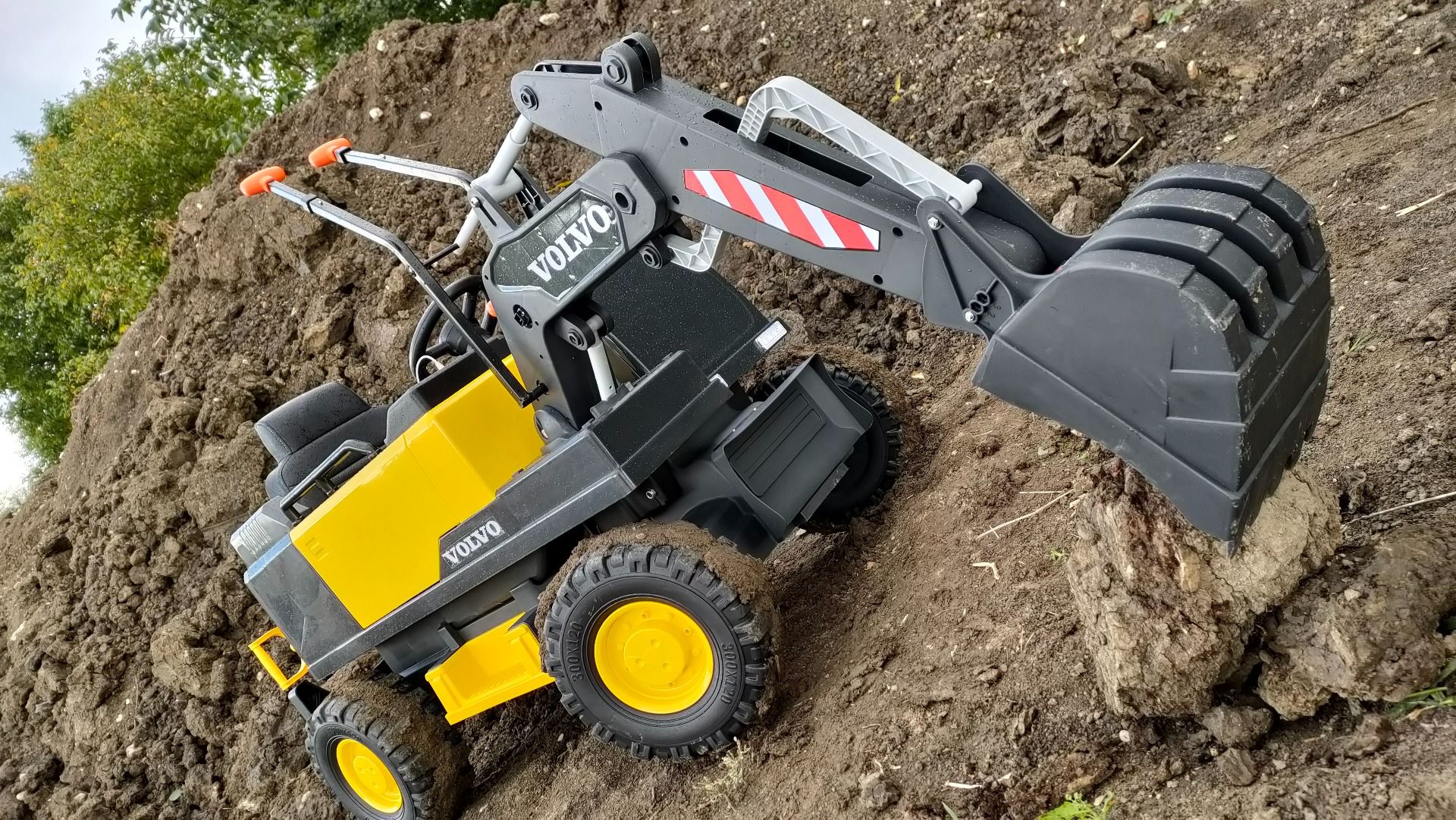 Elektrischer Bagger für Kinder Volvo Excavator 12V mit Baggerschaufel vorne, Einsitzer, gelb, weicher Kunstledersitz, MP3-Player mit USB/TF/AUX-Eingang, Heckantrieb, 2 x 35W Motor, EVA-Räder, 12V/14Ah Akku, lizenziert